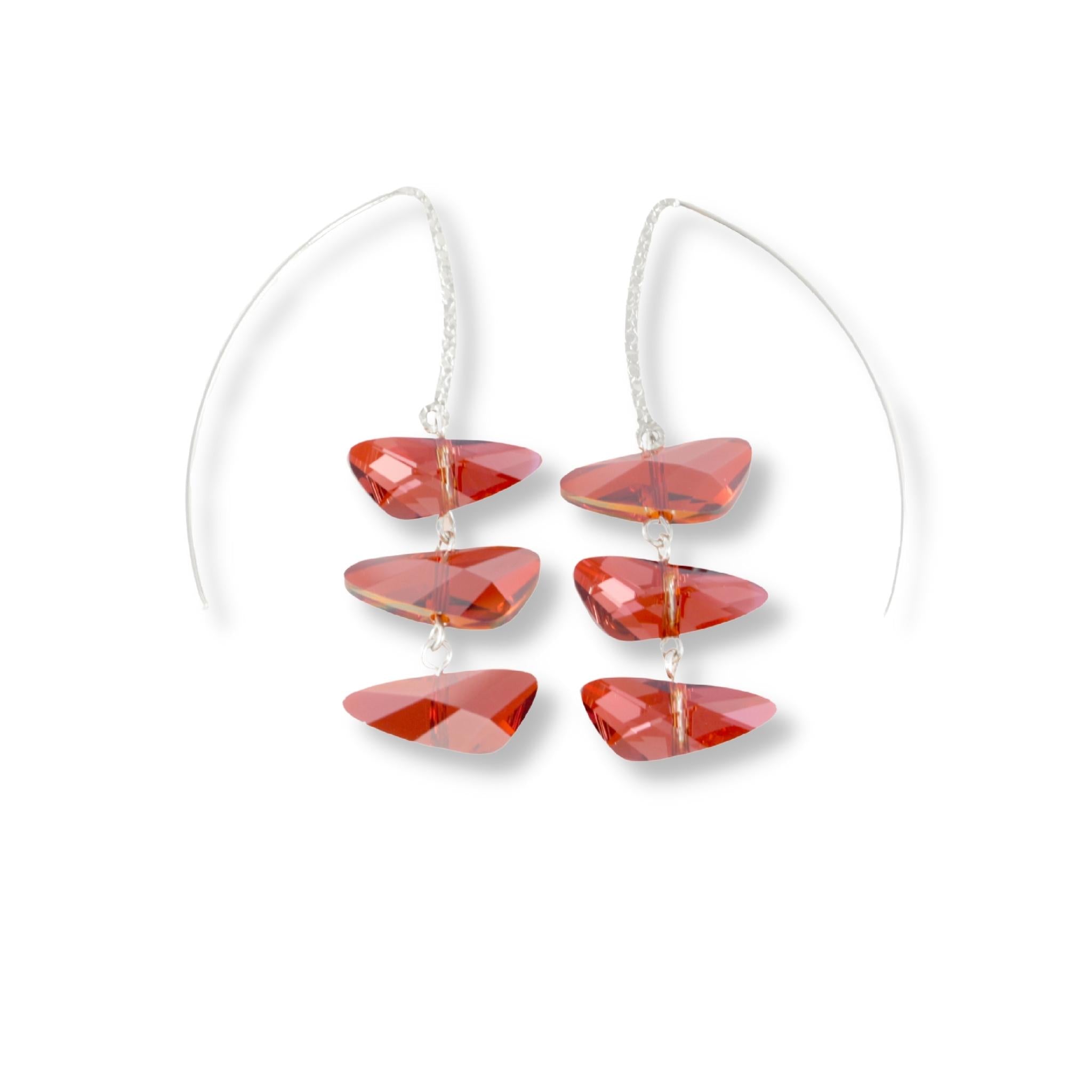 Wing shaped Swarovski crystal earrings in a reflective, deep cognac red color. The three crystal pendant is displayed on a long sterling silver marquise hook 